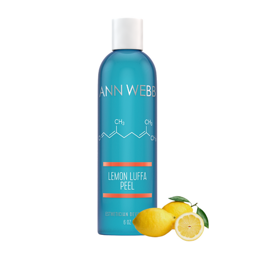 A bottle of Ann Webb Lemon Luffa Peel esthetician gel, featuring a bright blue bottle with a white cap and white text, accompanied by fresh yellow lemons and a lemon slice on a solid white background.